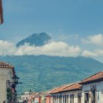 Charming street in Antigua Guatemala with a stunning view of a volcano under a clear blue sky.