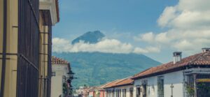 Charming street in Antigua Guatemala with a stunning view of a volcano under a clear blue sky.