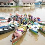 Colorful scene of a busy floating market with boats filled with produce on a river.